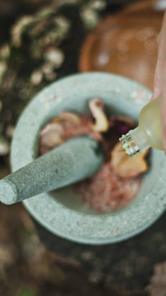 high angle photo of person pouring liquid from bottle inside mortar and pestle