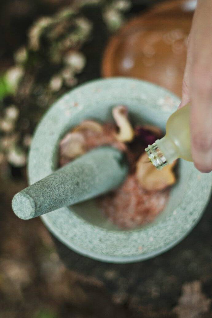 high angle photo of person pouring liquid from bottle inside mortar and pestle